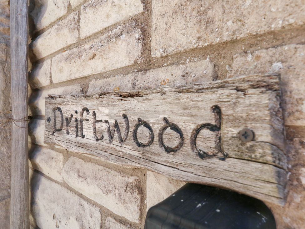 A wooden sign that reads Driftwood on a brick wall at Driftwood in Weymouth