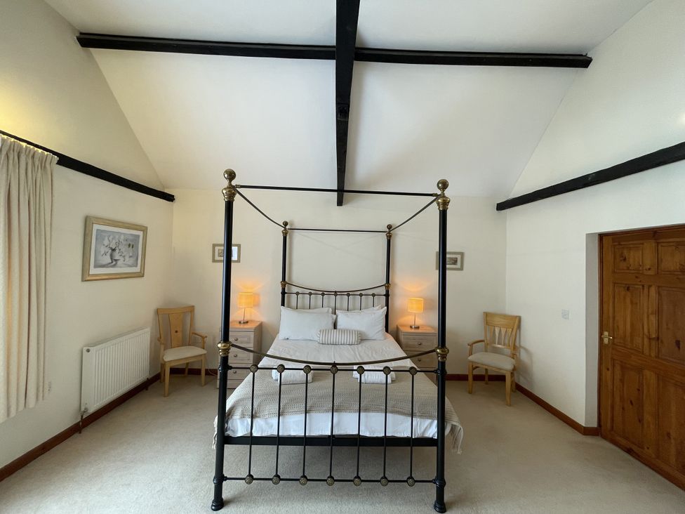 A bedroom with a four-poster bed and chairs at Beechwood in Wood Norton near Foulsham