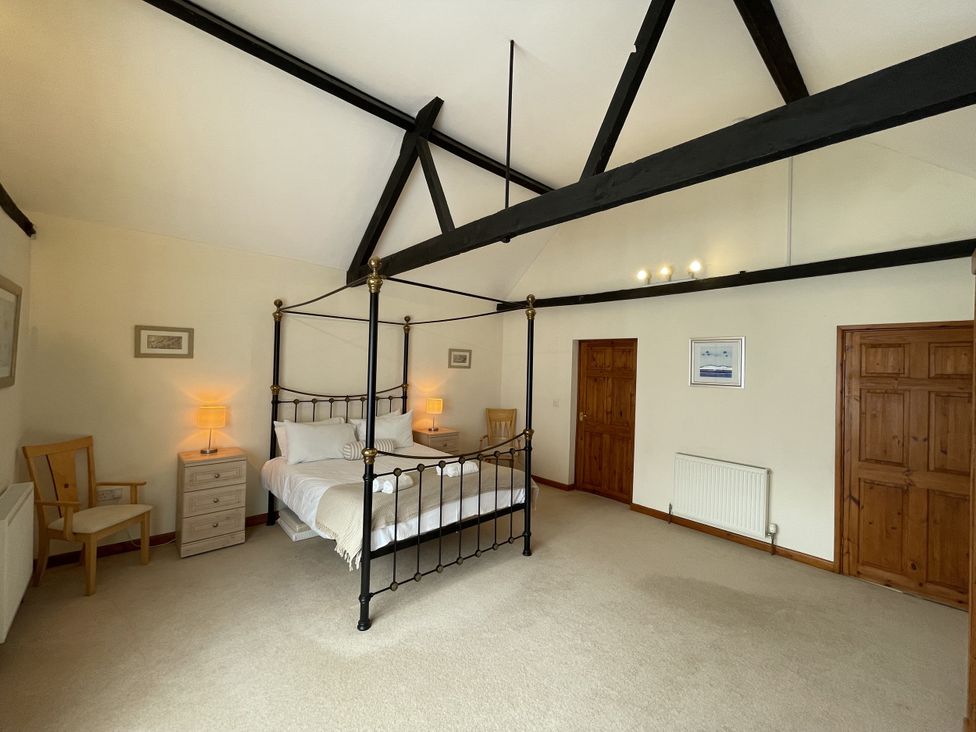 A bedroom with a four-poster bed and side tables at Beechwood in Wood Norton near Foulsham