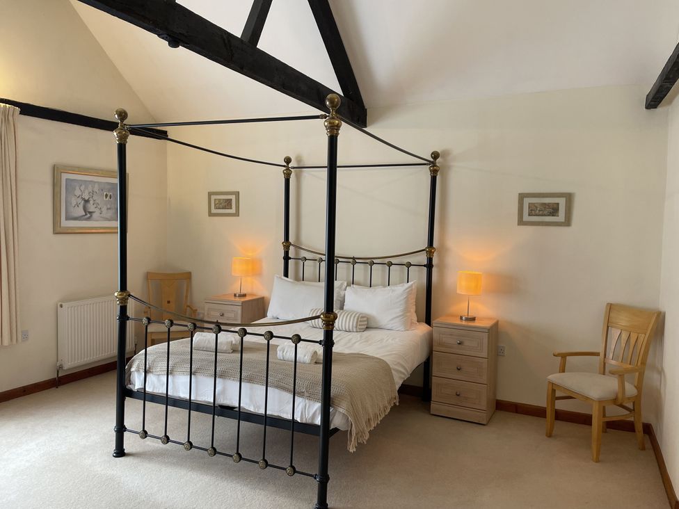 A bedroom with a four-poster bed and nightstands at Beechwood in Wood Norton near Foulsham
