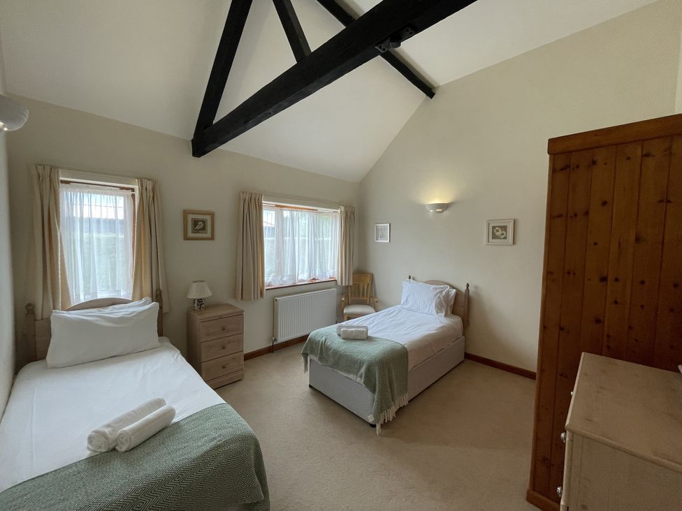 A bedroom with two beds and a wardrobe at Beechwood in Wood Norton near Foulsham