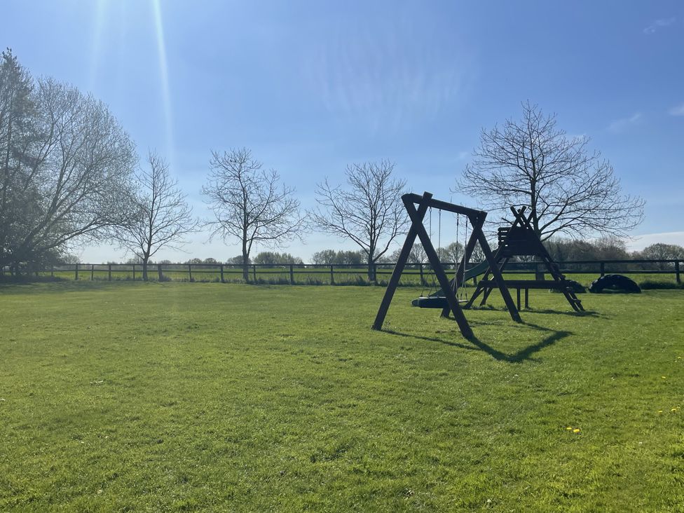 A swing set and slide on grass at Beechwood in Wood Norton near Foulsham