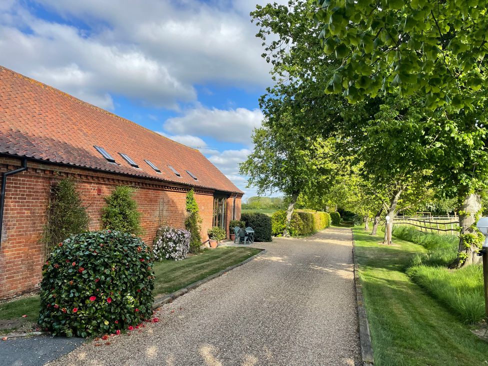A garden pathway leading to a house with trees and shrubs at Pear Tree in Wood Norton