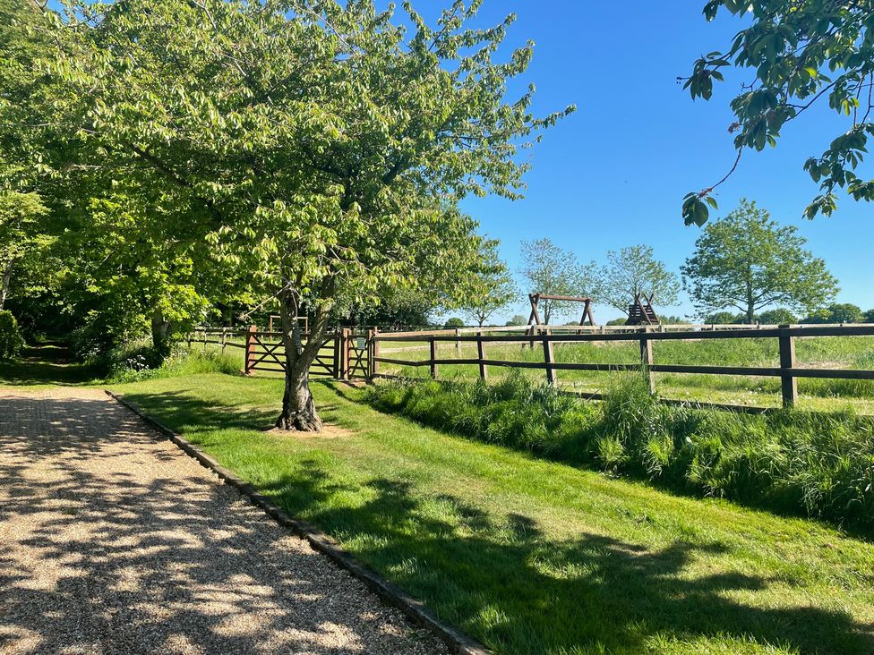 A garden with a tree and swingset at Pear Tree in Wood Norton