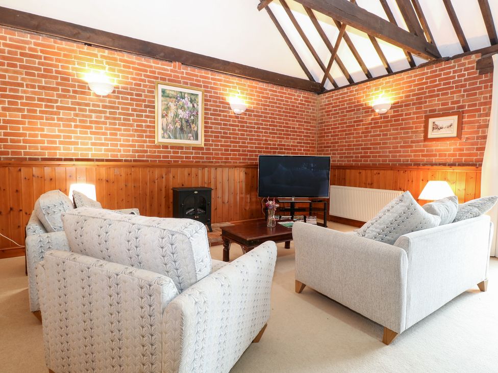 A living room with sofas and a television at Pear Tree in Wood Norton