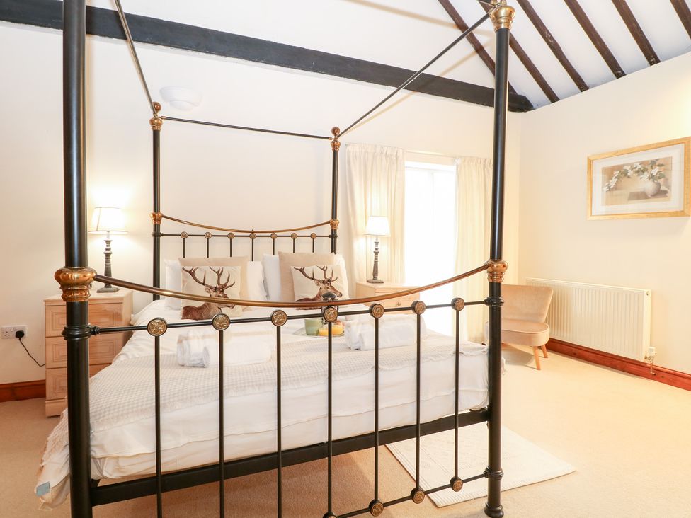 A bedroom with a four-poster bed and bedside lamps at Pear Tree in Wood Norton