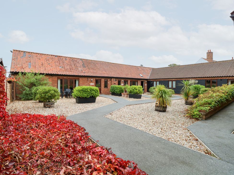 An outdoor courtyard with buildings and plants at Pear Tree in Wood Norton