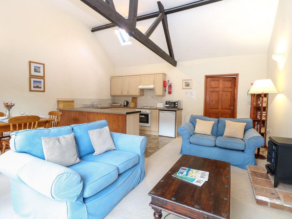 A living room with sofas and a kitchen area at Holly Berry in Wood Norton near Foulsham
