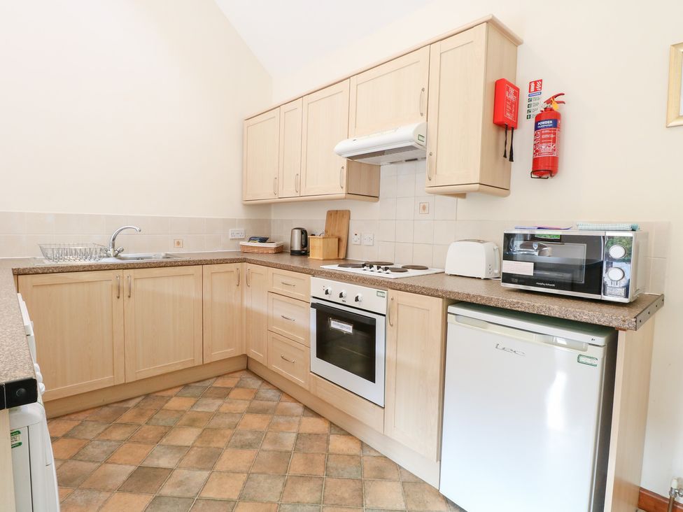 A kitchen with various appliances including a stove and fridge at Holly Berry Wood Norton near Foulsham