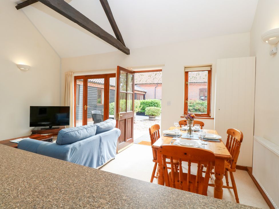A living room with a sofa and dining area at Holly Berry in Wood Norton near Foulsham