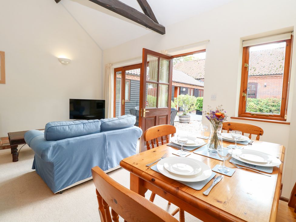 A living room with a sofa and dining table at Holly Berry in Wood Norton near Foulsham