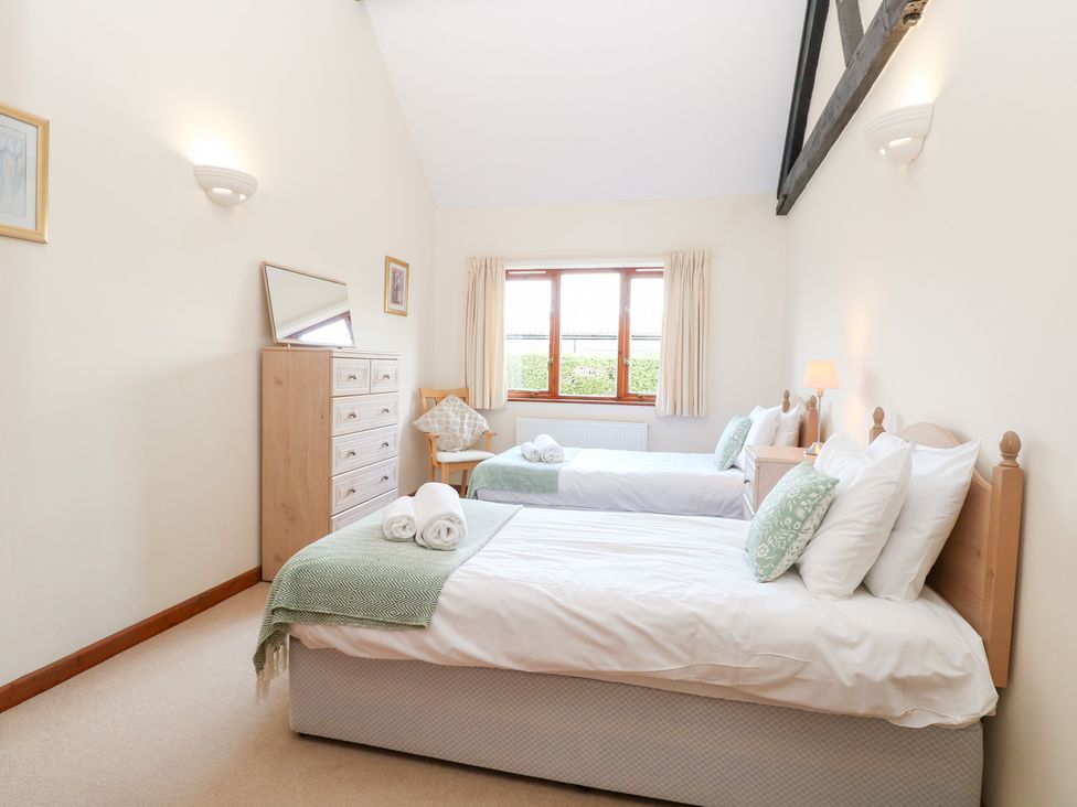 A bedroom with two beds and a dresser at Holly Berry in Wood Norton near Foulsham