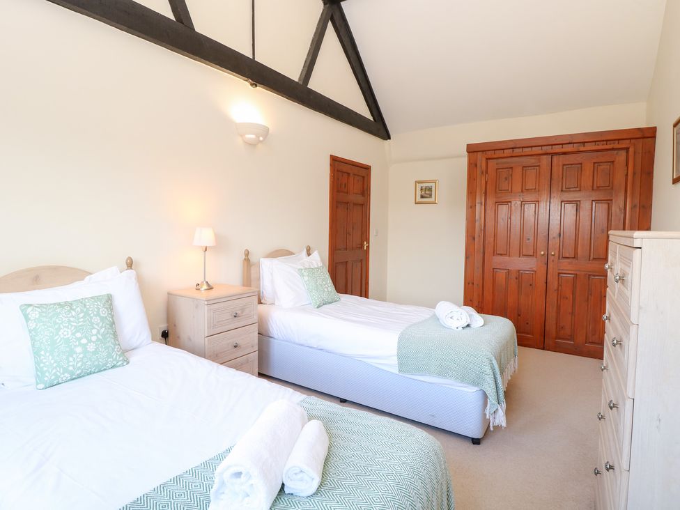A bedroom with two single beds and wooden furniture at Holly Berry in Wood Norton near Foulsham