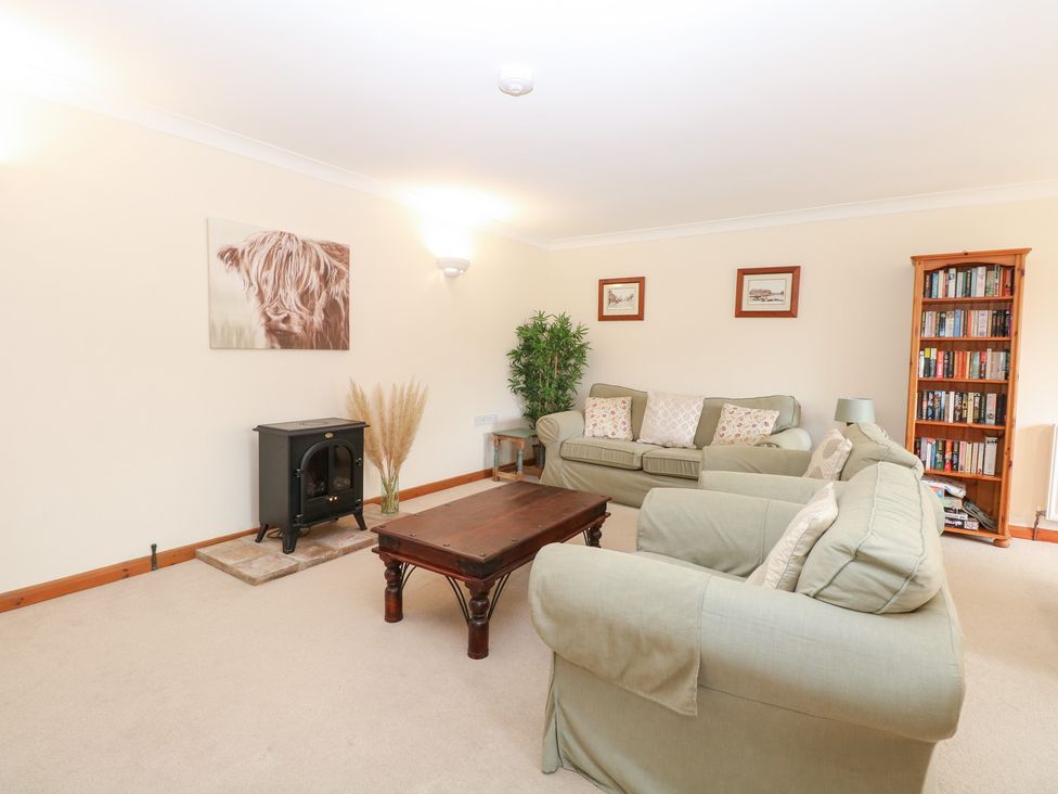 A living room with a stove and bookshelf at Sycamore, Wood Norton near Foulsham