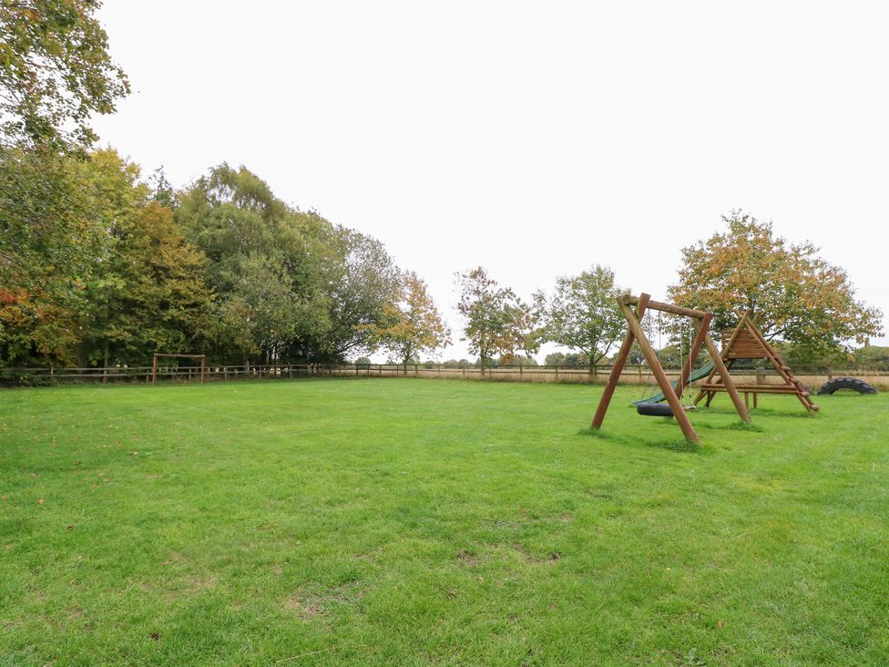 A garden with a swing set and trees at Sycamore, Wood Norton near Foulsham