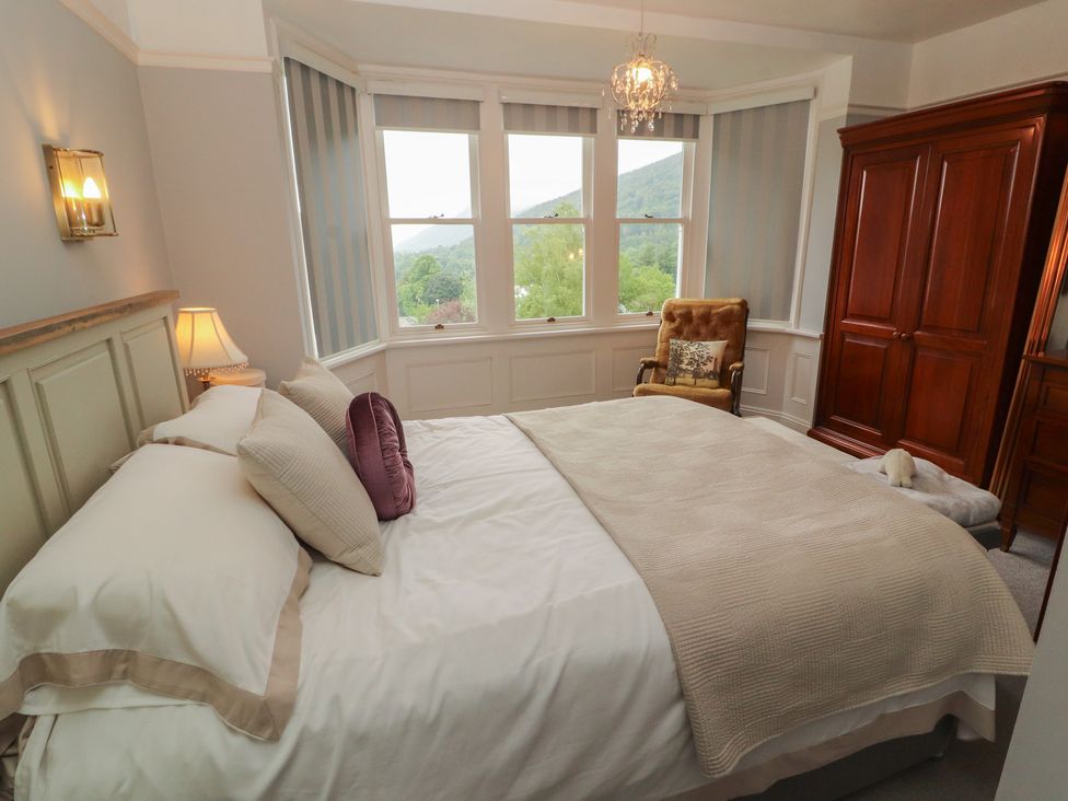 A bedroom with a bed and armchair at High Cross in Keswick
