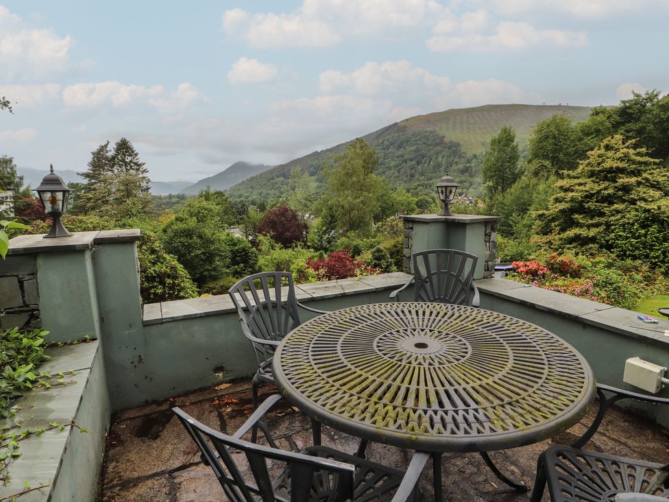A patio with a table and chairs overlooking mountains at High Cross in Keswick