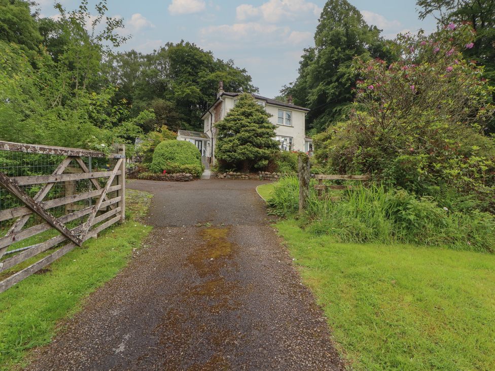 A driveway leading to a house with trees and a gate at High Cross in Keswick