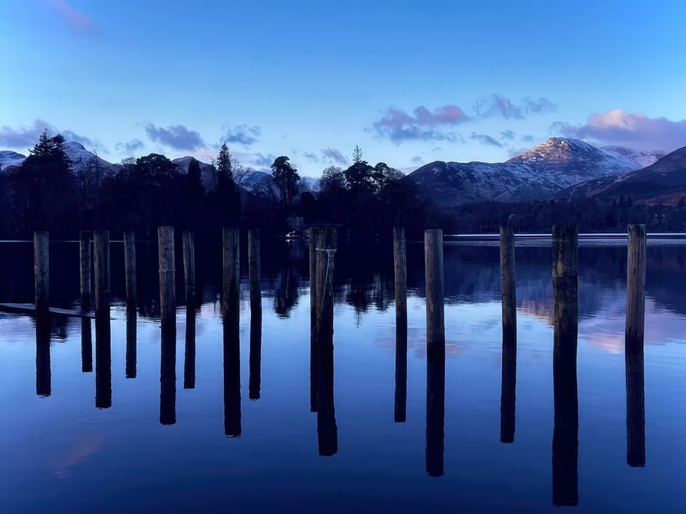 A view of wooden posts in water with mountains in the background at High Cross in Keswick