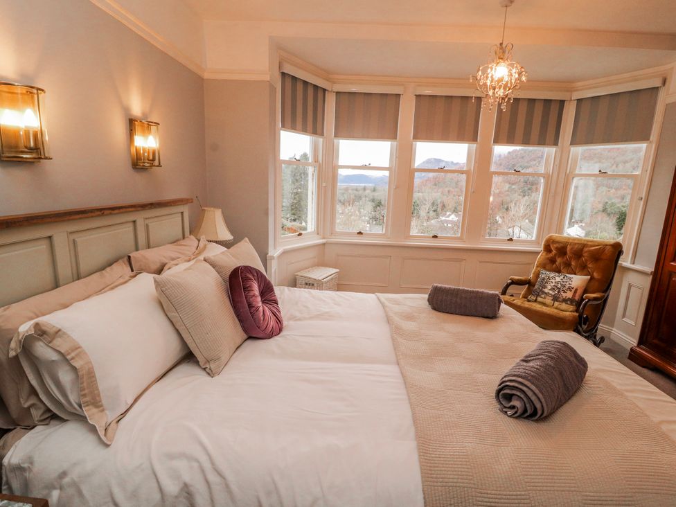 A bedroom featuring a bed, chair, and windows at High Cross in Keswick