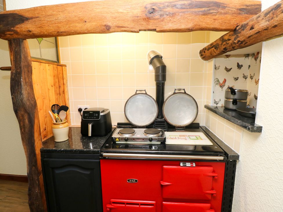 A kitchen with a red stove and cooking utensils at Dolcoed in Manordeilo near Llangadog