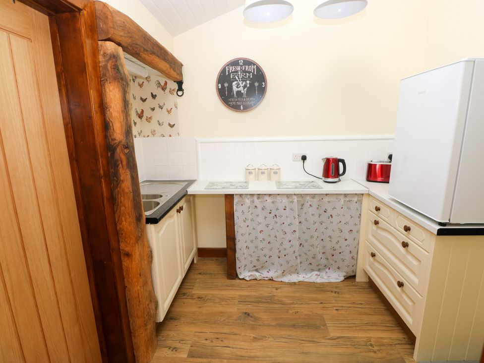 A kitchen with a sink, refrigerator, kettle, and cabinets at Dolcoed Manordeilo near Llangadog