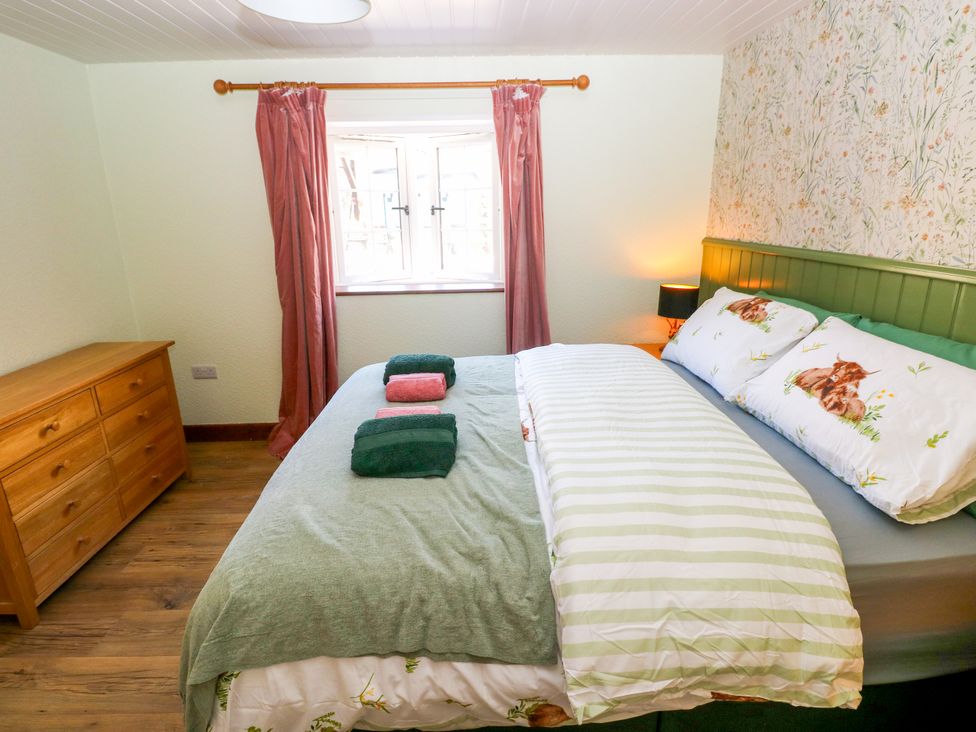 A bedroom with a bed and dresser at Dolcoed in Manordeilo near Llangadog