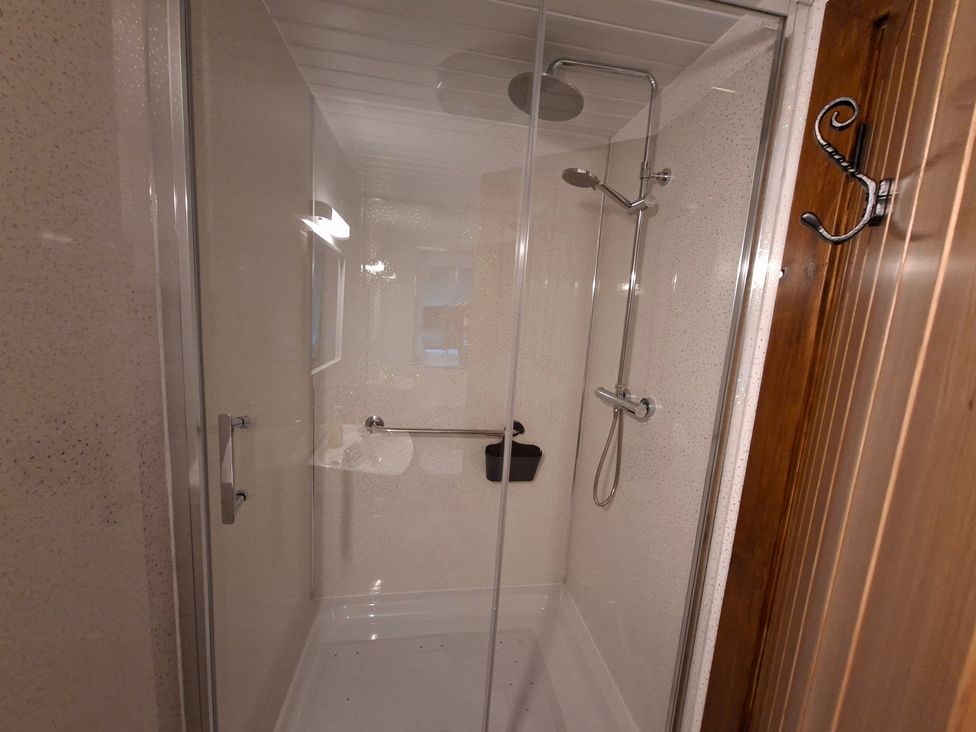 A shower with glass doors and fixtures at Dolcoed in Llandeilo