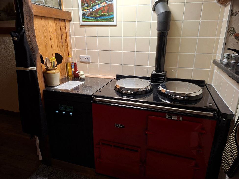 A kitchen with an AGA cooker and utensils at Dolcoed in Llandeilo