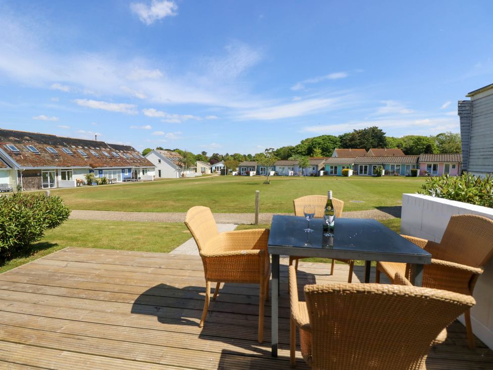 A patio with a black table and four wicker chairs overlooking a grassy area with rows of small houses at Cape 14 in Yarmouth