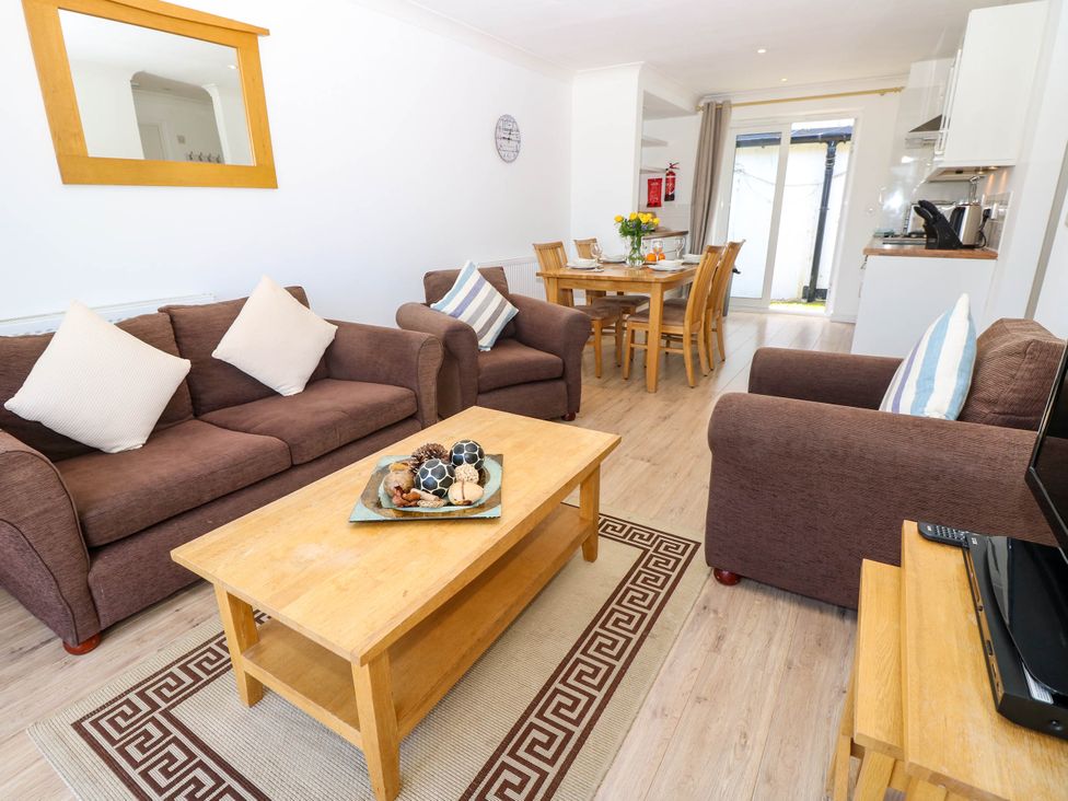 A living room with brown sofas a wooden coffee table and dining table at Cape 14 in Yarmouth