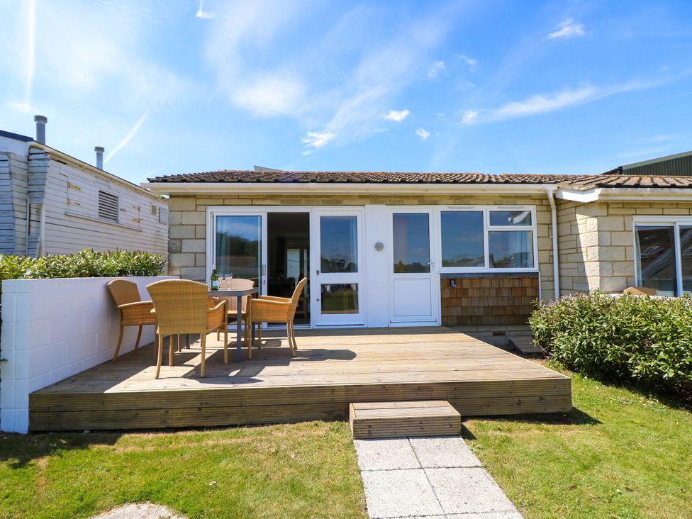 A wooden deck with a table and four chairs outside a single-story house at Cape 14 in Yarmouth