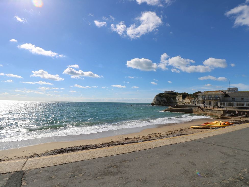 A beach with kayaks on the sand beside a concrete walkway and buildings near cliffs at Cape 14 in Yarmouth