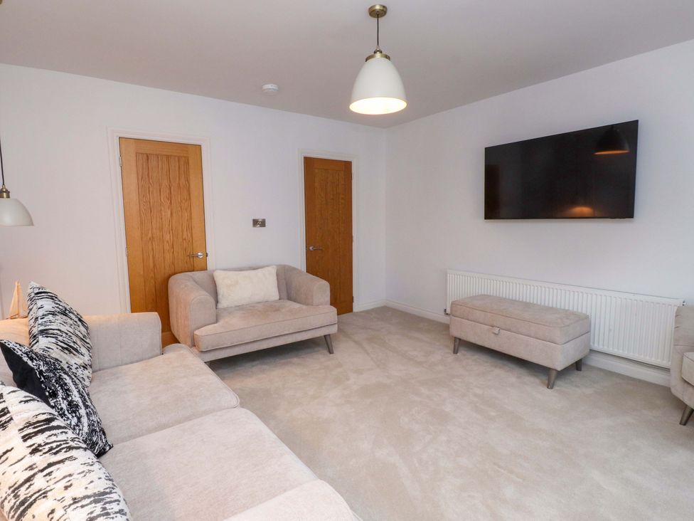 A living room with a sofa, armchair, television, and ottoman at 5 Lombard Street Porthmadog