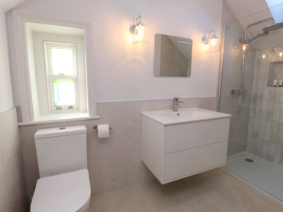 A bathroom with a shower, sink and window at 5 Lombard Street in Porthmadog