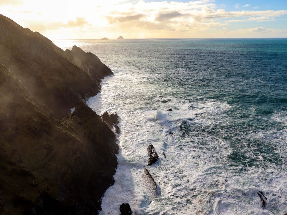 A coastal view showing cliffs, ocean waves, and distant islands at O'Conells in Portmagee