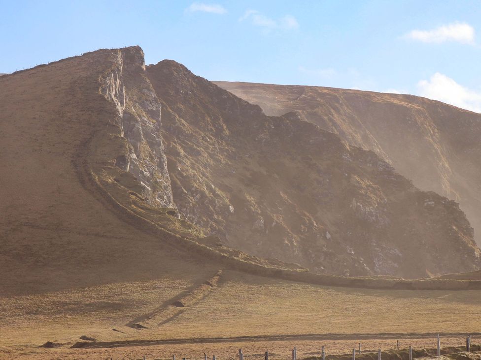 A cliff with a slope and grass at O'Conells in Portmagee