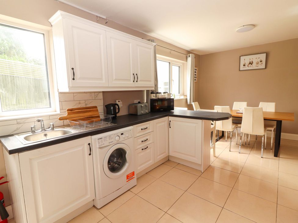 A kitchen with a washing machine and dining area at O'Connell's Lodge, Portmagee, County Kerry
