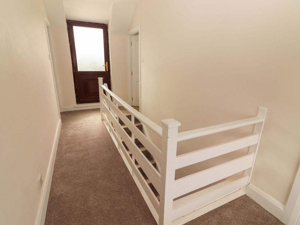 A hallway with a white railing and a door at O'Connell's Lodge, Portmagee, County Kerry
