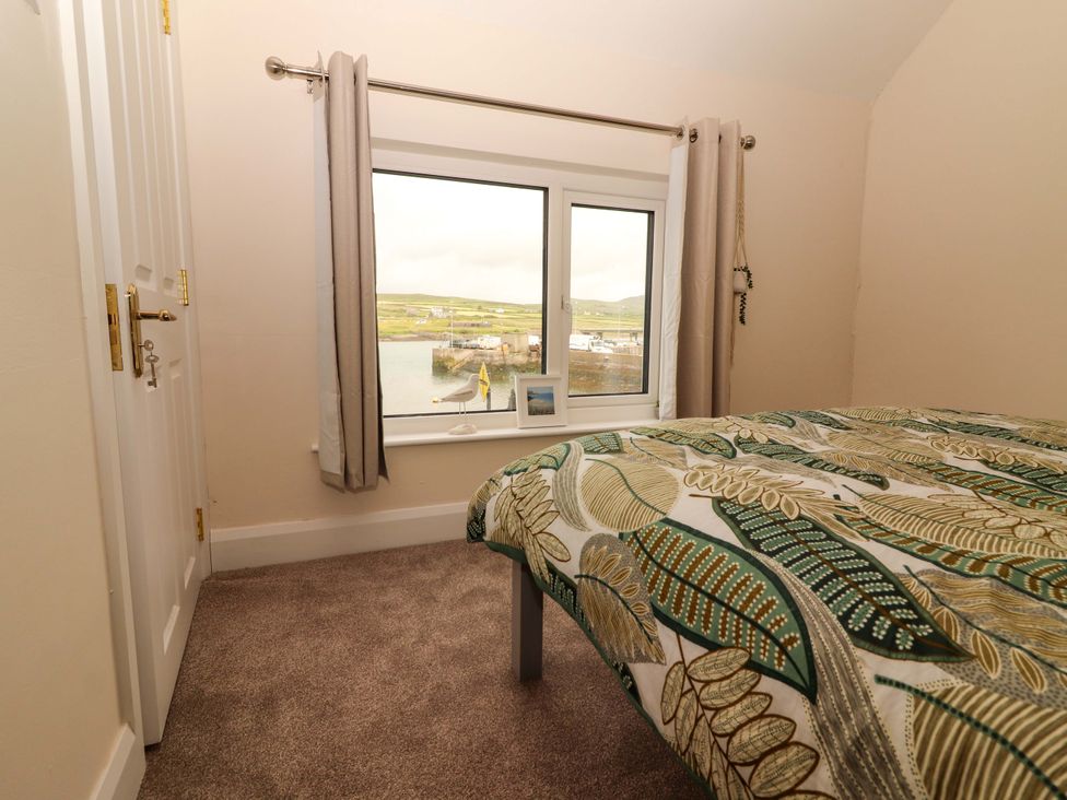 A bedroom with a bed and a window view at O'Connell's Lodge in Portmagee, County Kerry
