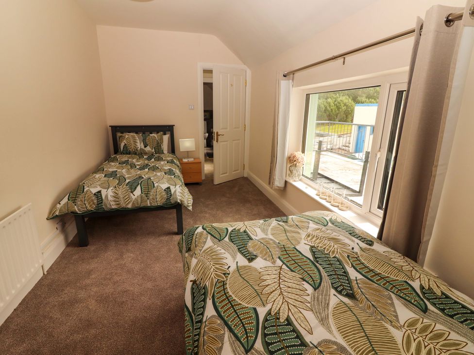 A bedroom with two beds and a window at O'Connell's Lodge in Portmagee, County Kerry