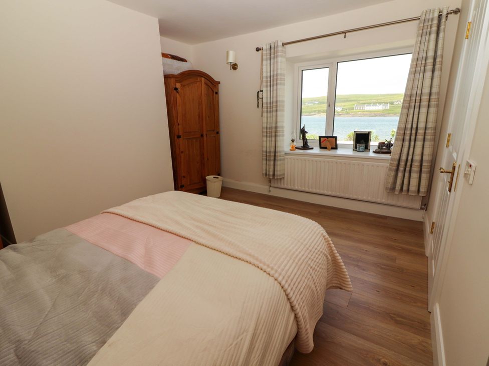 A bedroom with a bed and a window overlooking a body of water at O'Connell's Lodge, Portmagee, County Kerry