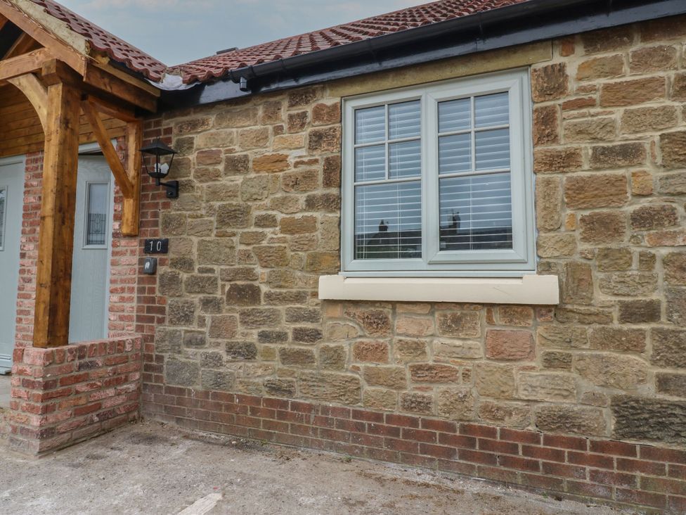 An exterior view of a cottage with a stone wall and a window at Cottage 10 in Brandon, County Durham