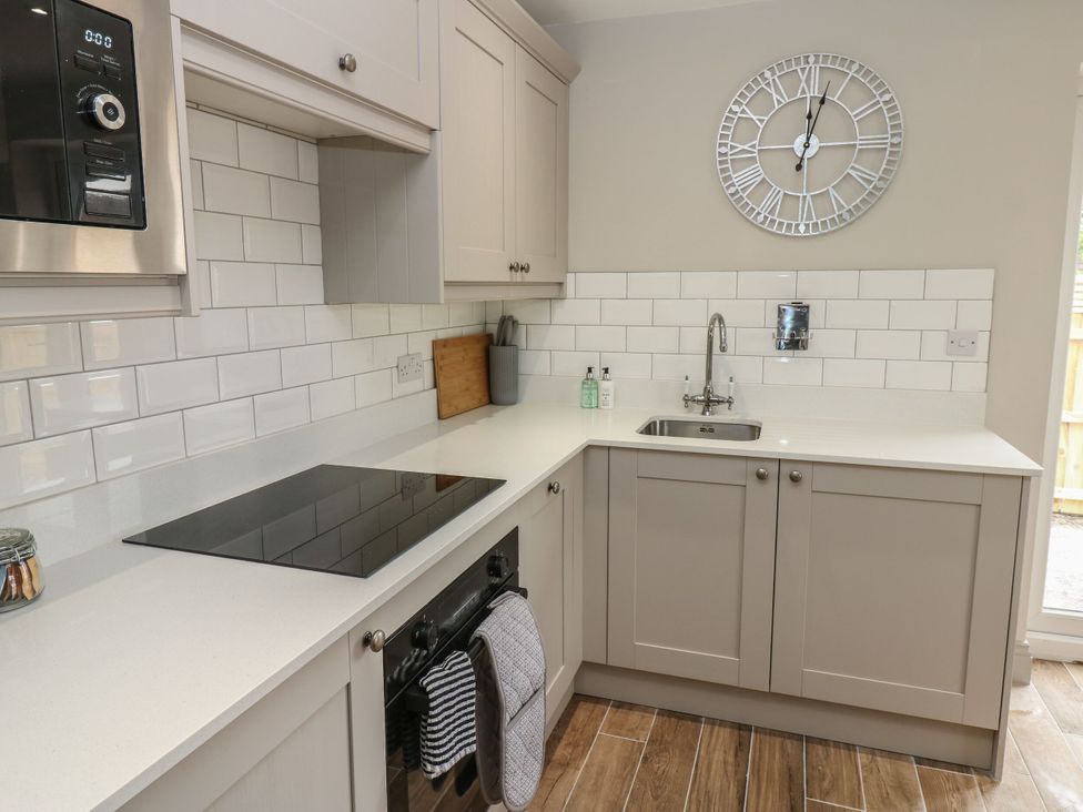 A kitchen with cabinets, an induction cooktop, and a sink at Cottage 10 in Brandon, County Durham
