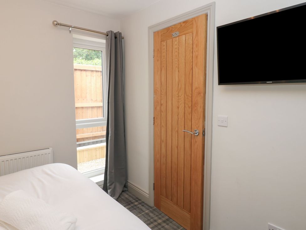 A bedroom with a bed, door, window, and TV at Cottage 10 in Brandon, County Durham