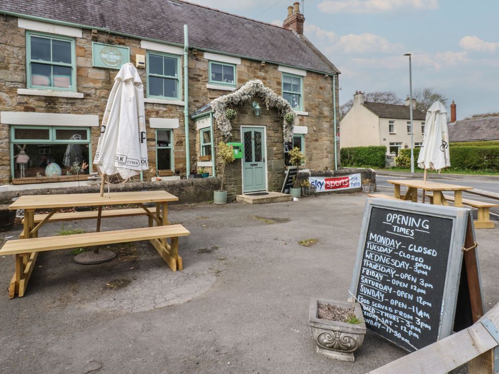 An outdoor seating area with tables and a menu board at Bay House in Brandon, County Durham