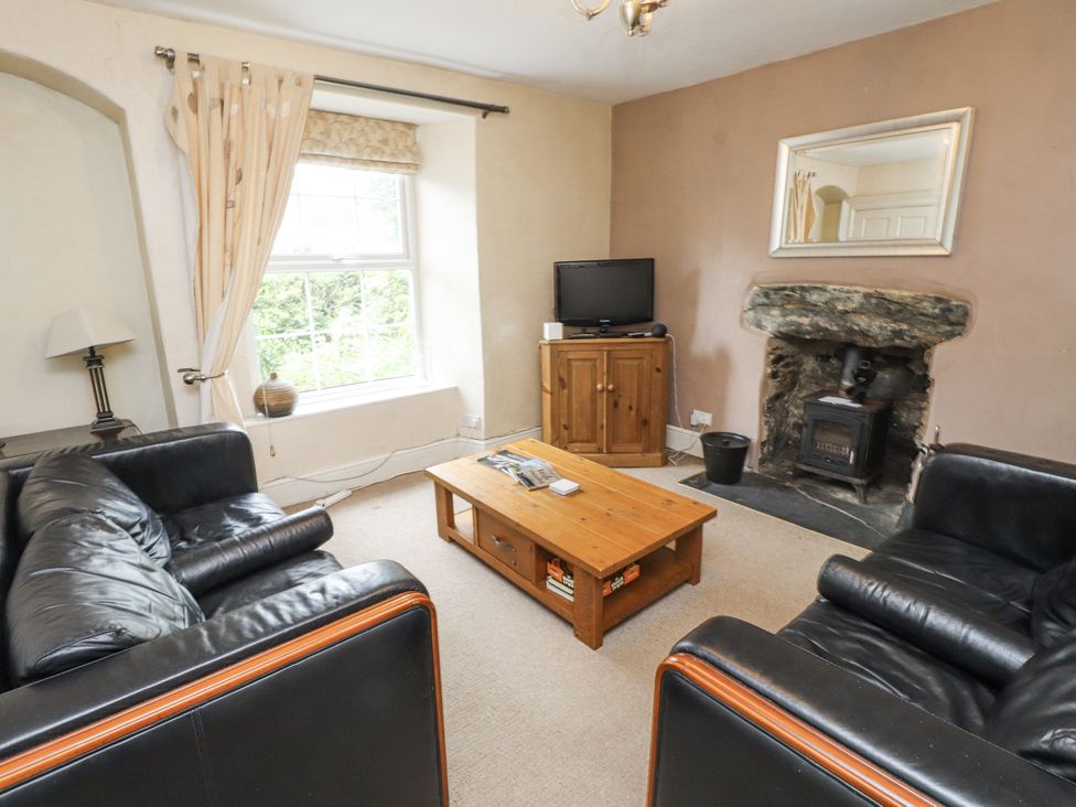 A living room with a sofa, coffee table, and television at Sygun Cottage in Nant Gwynant