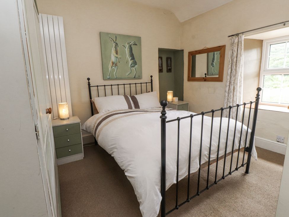 A bedroom with a bed and bedside table at Sygun Cottage in Nant Gwynant