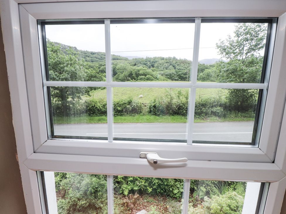 A window showing a view of grass and trees at Sygun Cottage in Nant Gwynant
