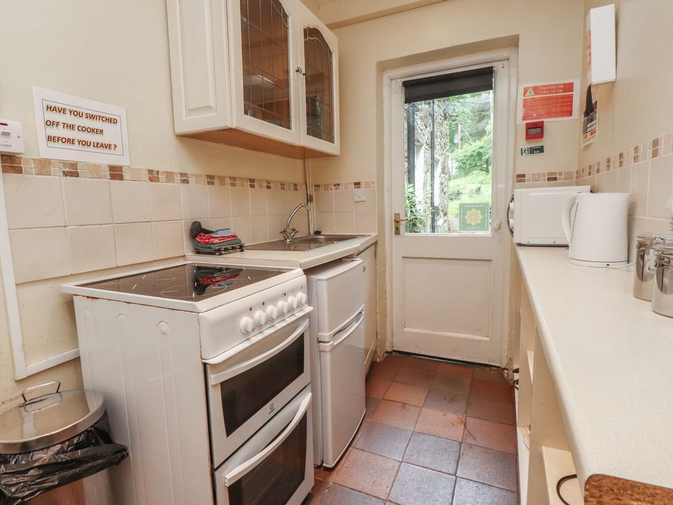 A kitchen with a cooker, sink, and cabinets at Tryfan Cottage, Nant Gwynant